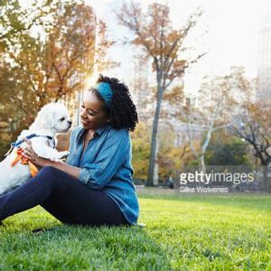 A woman sitting on the grass with her dog